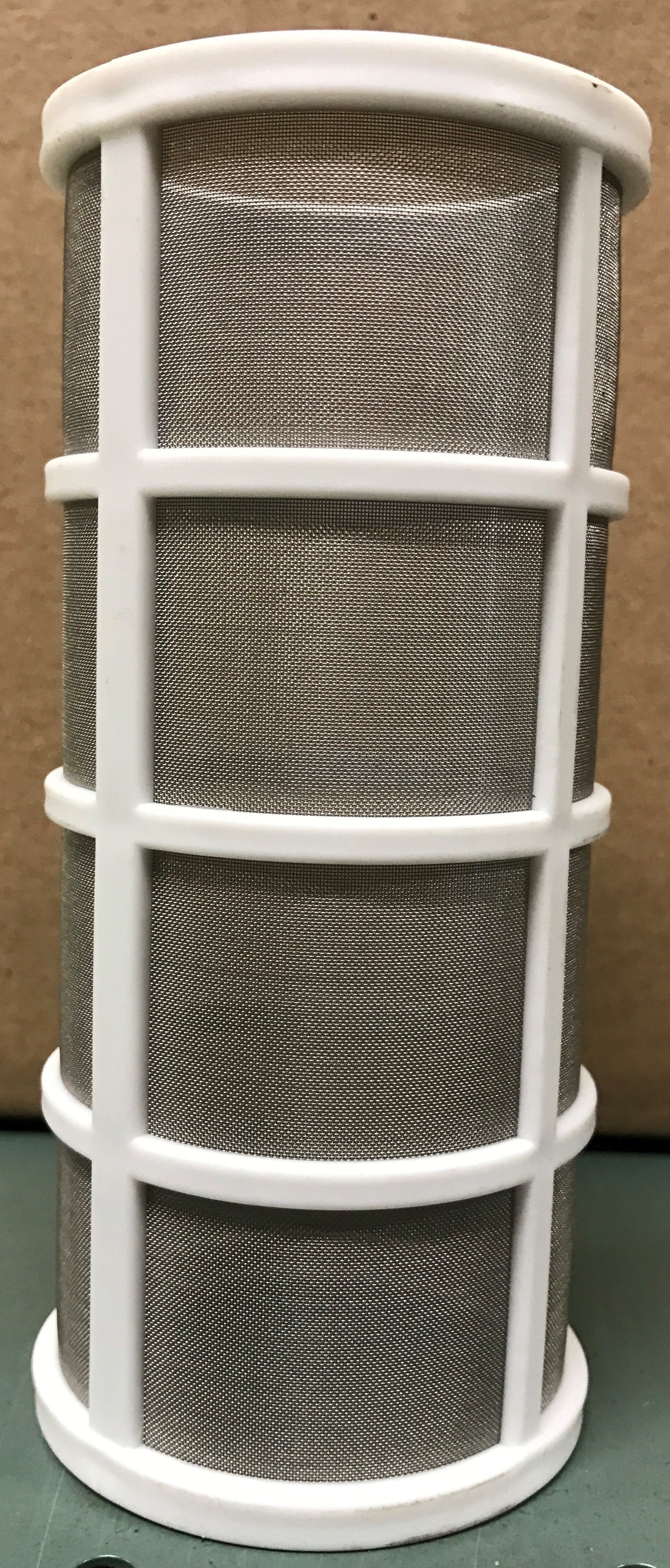 Air filter with white frame and gray pleated media on a green surface.