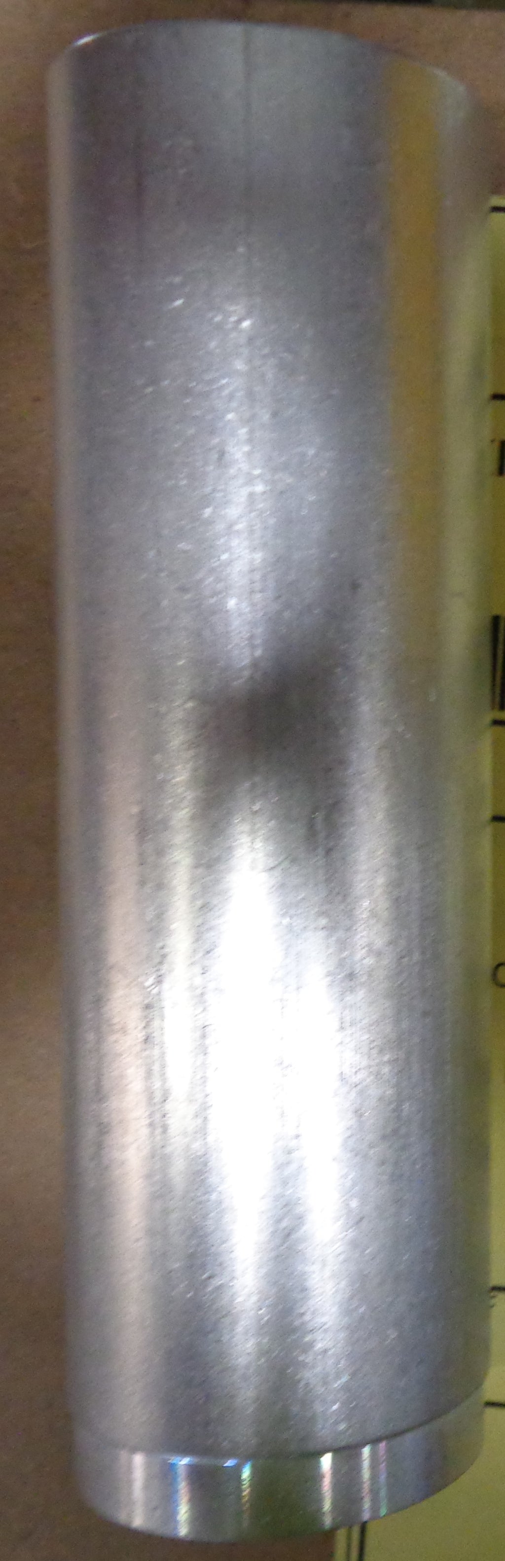 Metal cylindrical object with a textured surface on a brown background