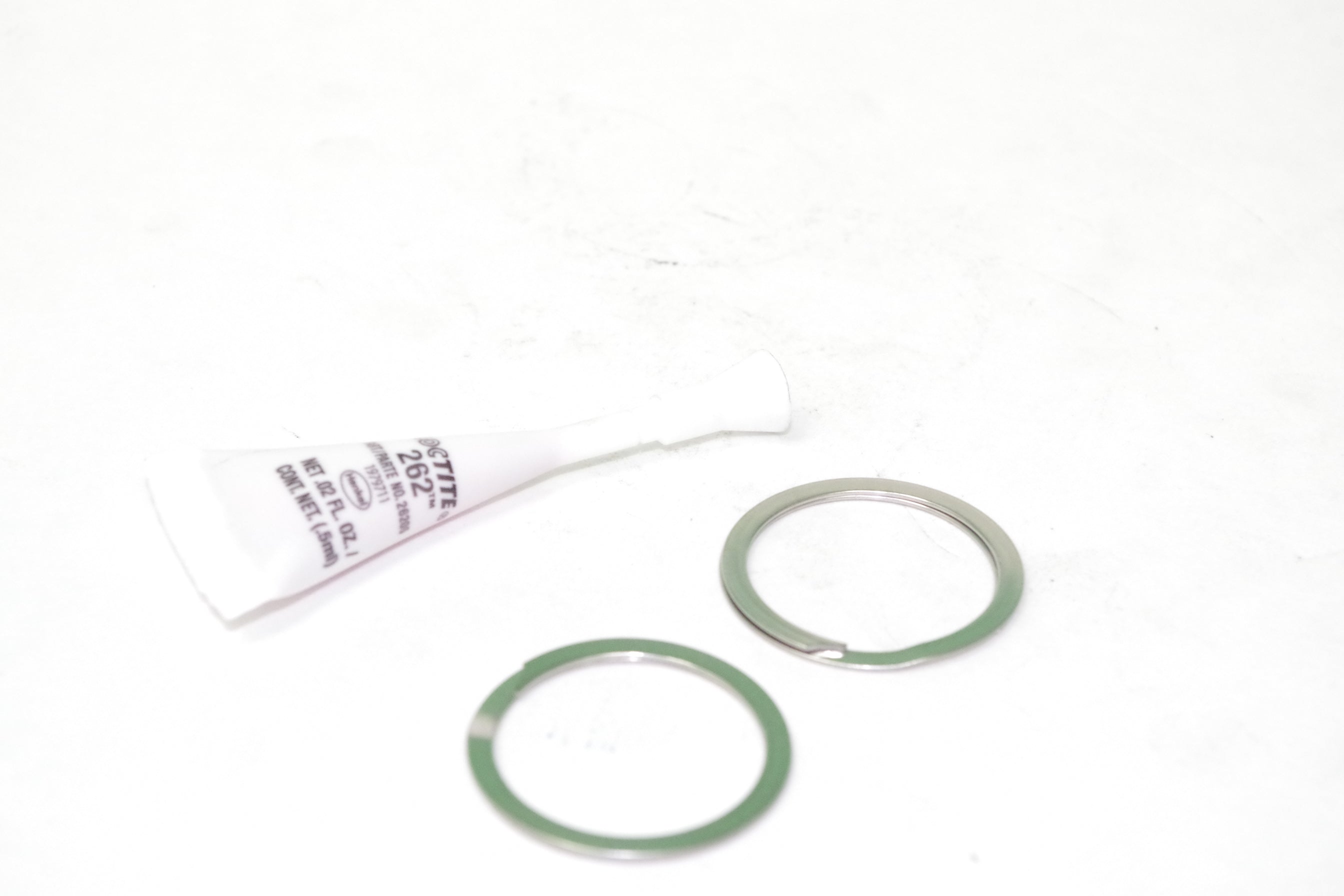 Two gaskets and a small tube on a white background