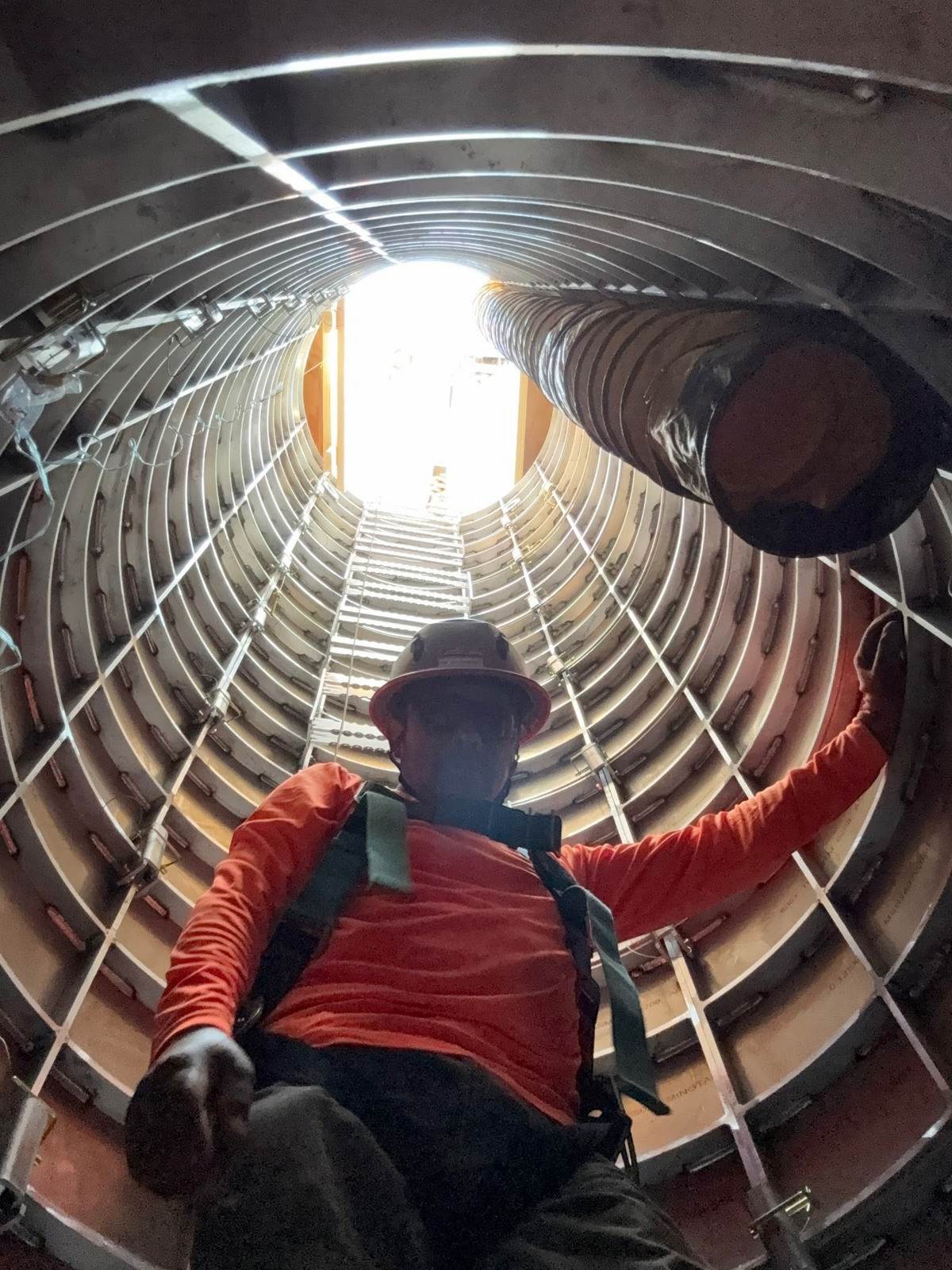 Worker inside a Sewershop EasyDig modular circular trench cage, viewed from below during hydrovac excavation.