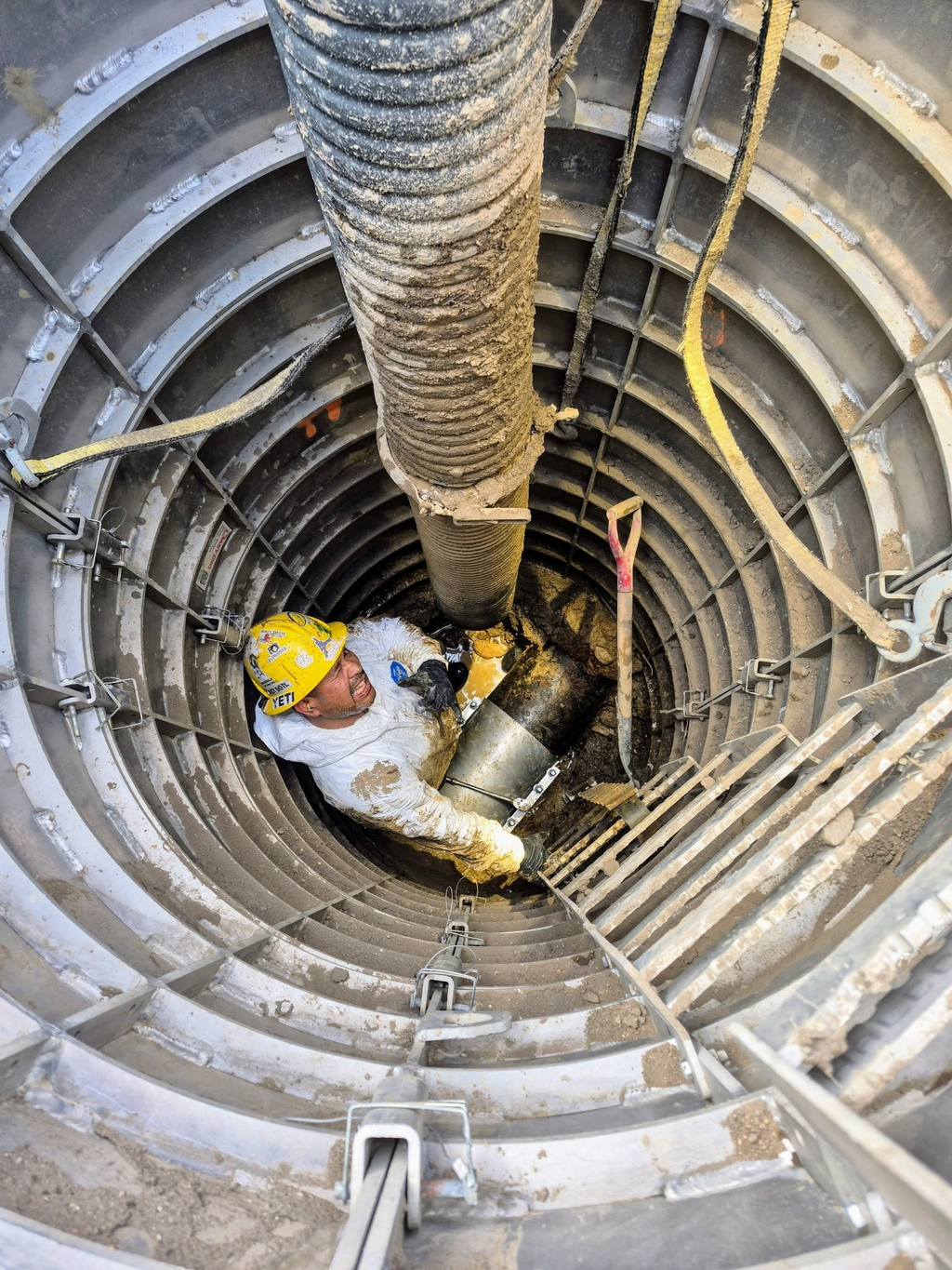 Worker in a Sewershop EasyDig modular circular trench cage using a hydrovac hose for underground utility repair