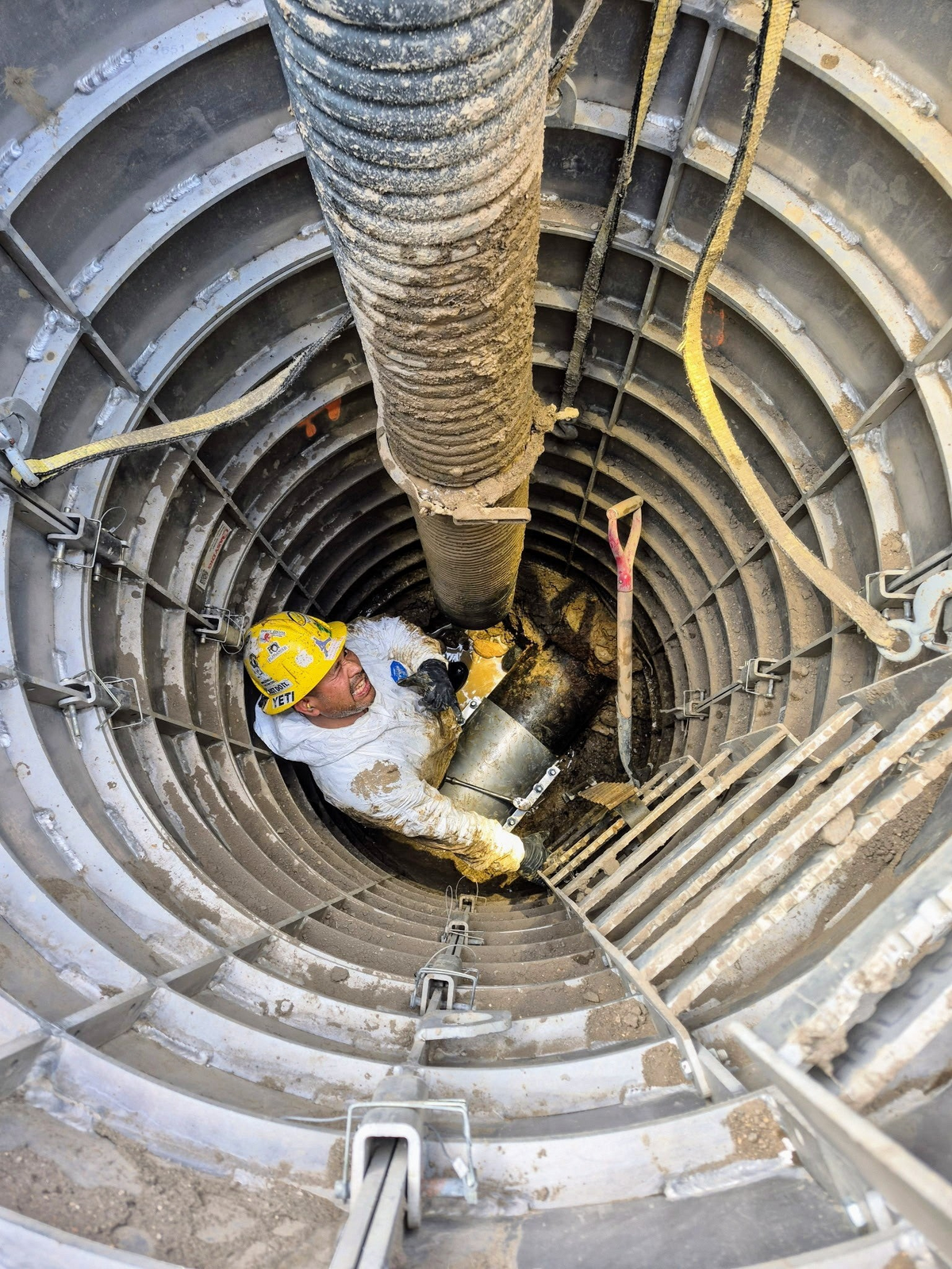 Worker in a Sewershop EasyDig modular circular trench cage using a hydrovac hose for underground utility repair